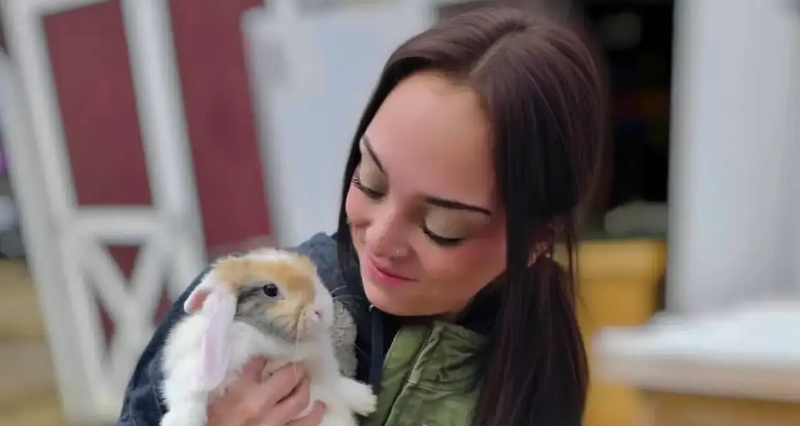 Woman holding a cute bunny rabbit, smiling gently.